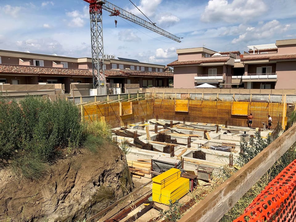 Cantiere di un complesso residenziale con gru e scavo delle fondazioni